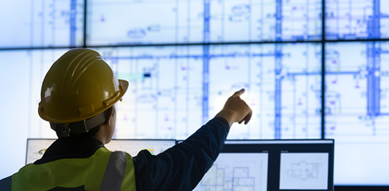 Enginner looking over data center blue prints on screen, 560 x 275